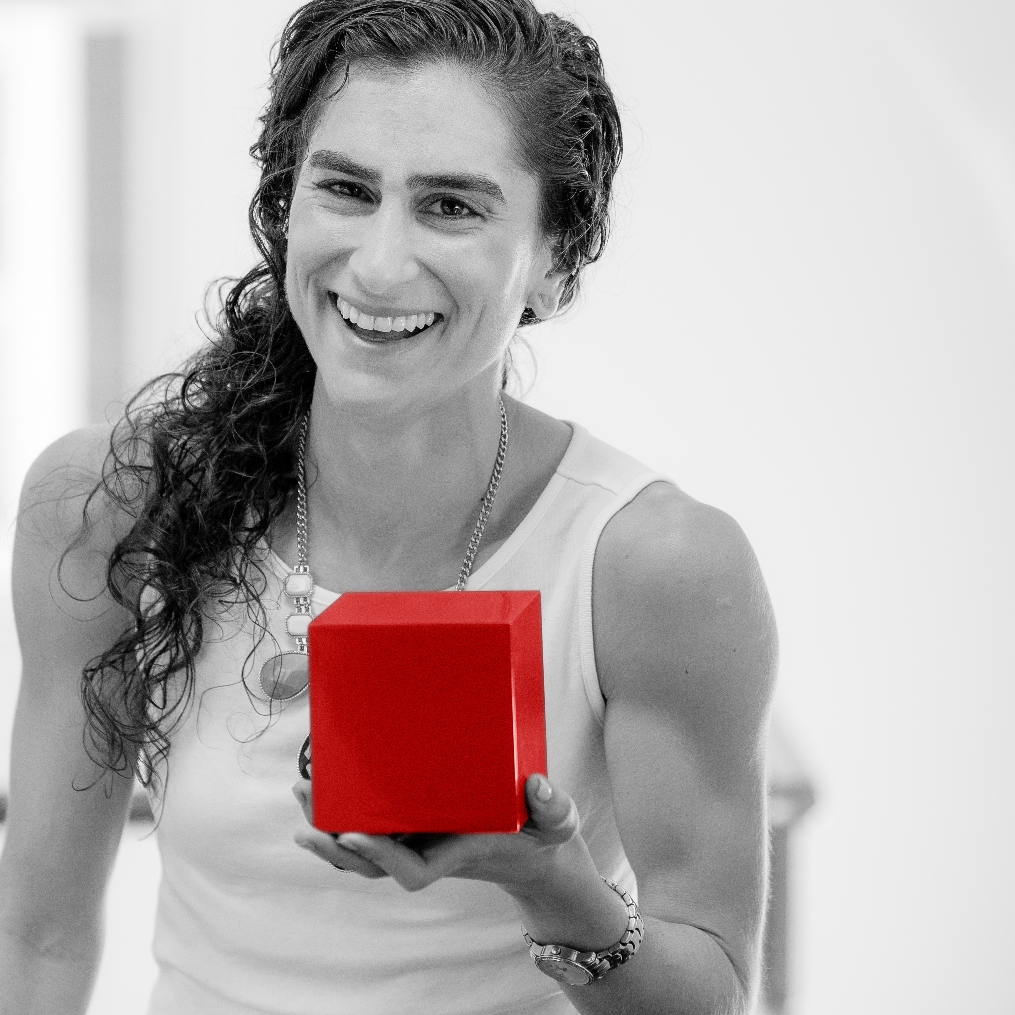 Samar T Pants smiling in black and white while holding a bright red cube